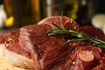 Spices, oil and board with raw steak meat on wooden background