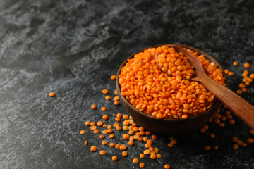 Bowl and spoon with red legumes on black smokey background