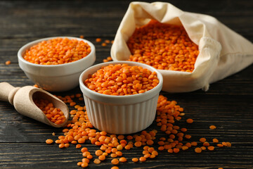 Bag, scoop and bowls with red legumes on wooden background