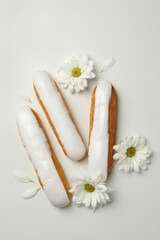 Fototapeta na wymiar Delicious eclairs with custard and chamomiles on white background