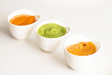 Three famous Canary islands sauces Mojo picon , Red hot sauce, and  Mojo verde , Green sauce and Almogrote, cheese  sauce  in bowl on white background