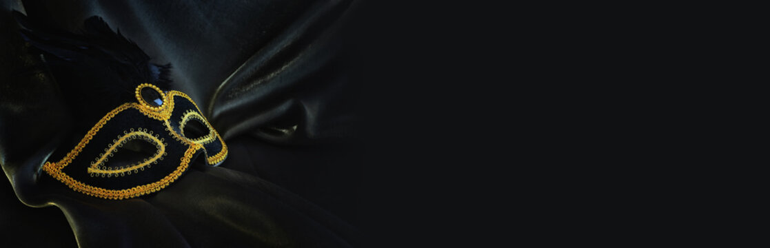 Photo of elegant and delicate Venetian mask over dark silk background