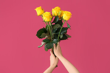 Hands with beautiful yellow roses on color background