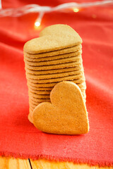 Pile of Valentine's day cookies with heart shape isolated on red with ethereal lights on the background. Valentine's day and love concept. Vertical photo. Selective focus