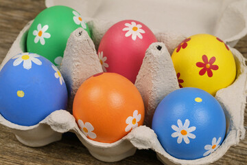 Colorful painted Easter eggs  in a paper tray on a wooden table