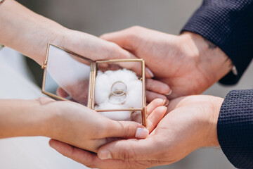 wedding rings in the hands of the bride and groom. Gold rings in a decorative glass box with cotton - 404753498