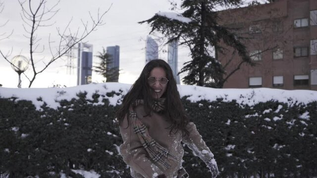 Mixed race woman throwing snowball to the camera