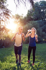 Two young sporty man and woman exercising in park at summertime season.