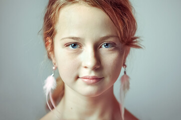 Close-up portrait of a young girl with festive makeup for a party. Valentine's Day. Earrings-feathers in the ears of the model