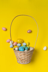 Basket with scattered Easter eggs. Top view on festive eggs. Bright yellow background