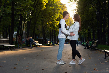 Date in park. Guy and girl hug in park on setting sun background.