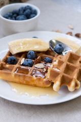 Breakfast with Belgian waffles with honey, blueberries, banana and almonds  on a linen tablecloth. 