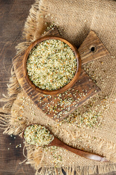 Hemp seeds. Peeled whole dried hemp seeds in a wooden bowl on a wooden table. Hemp seeds for cooking