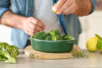 Male hands preparing healthy dinner of baked broccoli at home kitche