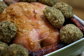 Roasted chicken in dish with balls of sage and onion stuffing and sausages.