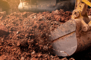 Closeup bucket of backhoe digging the soil at construction site. Crawler excavator digging on...