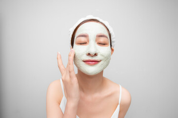 Beauty shot of Asian cute girl with beautiful skin shows mask cream on her face over white background.