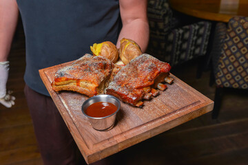 Grilled pork ribs served in a restaurant or diner. Waiter service, eating out concept.