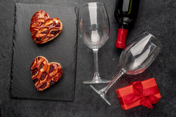 Fototapeta na wymiar Two heart shaped pies, red wine and glasses on a stone background .Valentine's day celebration concept