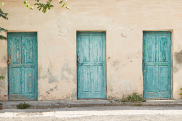 old turquoise doors against a beige wall