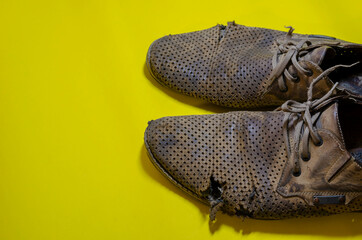 Old torn yellow summer shoes on a yellow background
