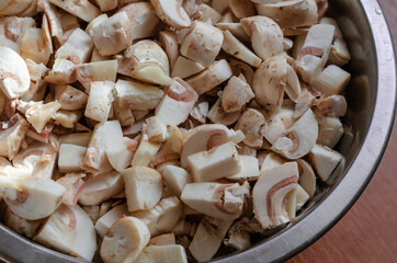 Raw mushrooms diced in a metal bowl.
