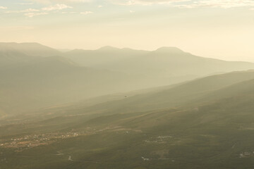 the sun's rays break through the smog on the city located at the foot of the mountains