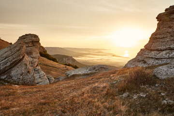 view from the hill with dried grass and low mountains on the coast and the rising sun