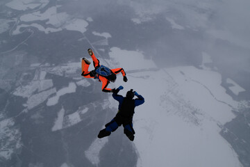 Skydiving. Two skydivers are training in the winter sky.