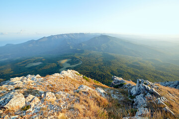 view from the rocky mountain to the forest plain and mountains in the distance