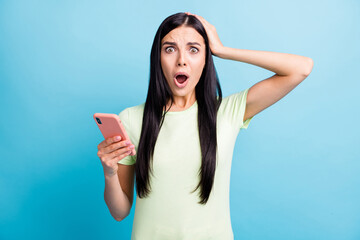 Photo portrait of worried girl touching head holding phone in one hand isolated on pastel blue colored background