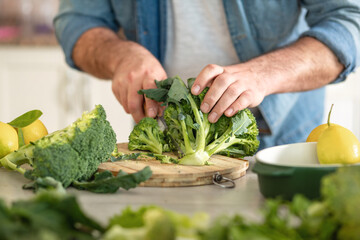 Man preparing delicious and healthy lunch of broccoli at home kitchen