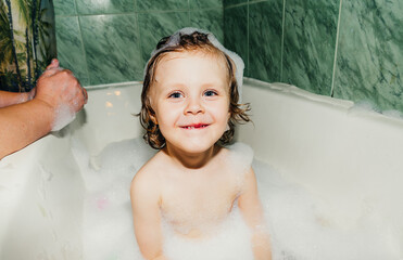 beautiful child toddler son washes in the bathroom plays has fun with soap bubbles,foam