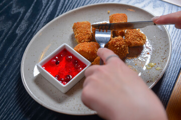 Fried camembert cheese in breading with cranberry sauce served on a white plate. Still life, eating out concept.