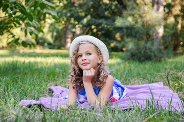 little joyful happy girl in a dress is resting in the park on the grass