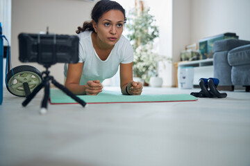 Serious dark-haired vlogger performing the core-strengthening exercise