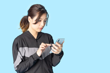 Fototapeta premium スマホを使うトレーニングウェアをきた女性