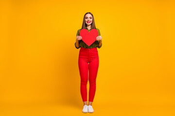 Fototapeta na wymiar Full length body size view of nice cheerful straight-haired girl holding in hands heart isolated on bright yellow color background