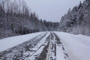 Obraz premium Overtaking on the opposite lane is prohibited. Road signs prohibiting overtaking in the opposite lane on the highway. The ice-covered winter track is dangerous. Drifts on the road.
