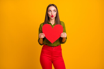 Portrait of lovely coquettish straight-haired girl holding in hands heart sending air kiss isolated...