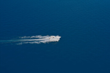 Aerial view of a boat in motion on blue water. Top view of a white boat sailing in the blue sea. Drone view of a boat sailing at high speed. luxury motor boat.