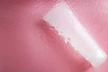 moisturizing skin care products. Face and hand cream under a glass surface with water on a pink background. spa cosmetic