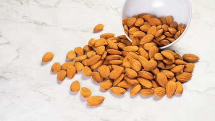 Almonds  pour from white porcelain bowl on the table.Healthy food Concept.