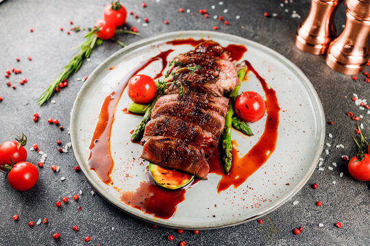 Gourmet Chateaubrian Steak From Filet Mignon With Grilled Vegetables In A Sauce In The Serving On A White Plate On A Gray Background