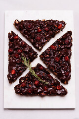 Mosaic Chocolate and Biscuit Cake with Nuts and Dried Cherries on white marble board. Chocolate and cookie dessert. Christmas delicious treat. Selective focus