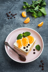 Sponge cake layers with buttercream, decorated with slices of tangerine chocolate and mint. Delicious sweet dessert for tea.