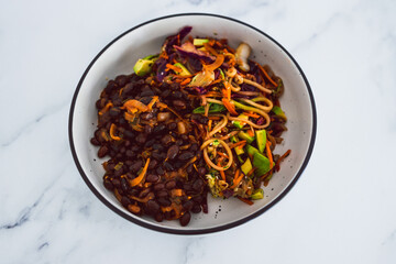 healthy plant-based food, vegan nourish bowl with mexican beans and mixed veggies coleslaw topped with sesame seeds