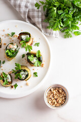 Roasted zucchini rolls stuffed with cheese on white plate. Top view