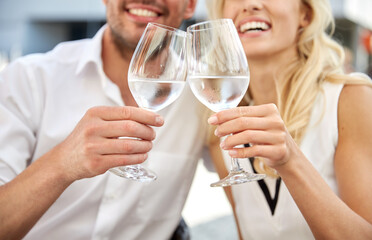 Fototapeta na wymiar love, dating and people concept - close up of happy couple drinking water and clinking wine glasses at restaurant
