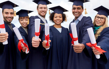 education, graduation and people concept - group of happy international graduate students in mortar...